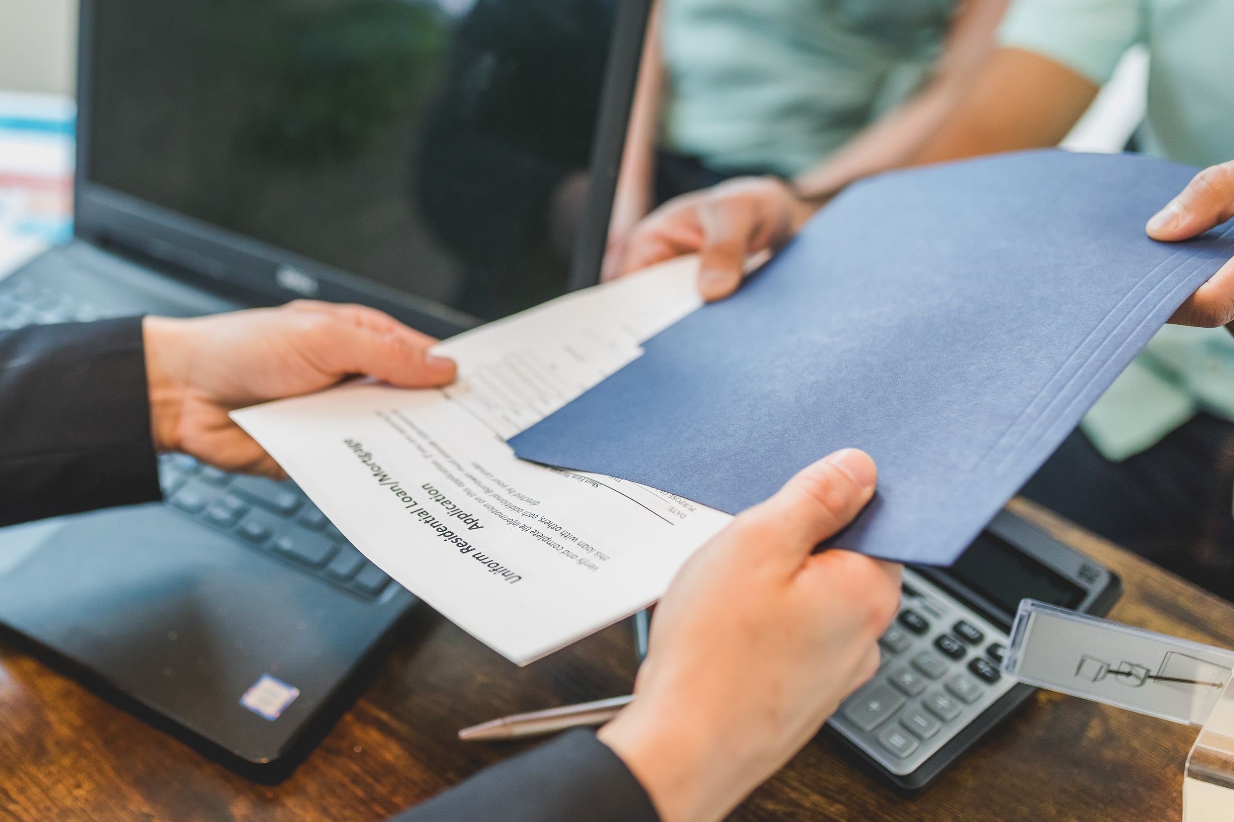 A notary's desk with a pen, a folder of documents and a laptop