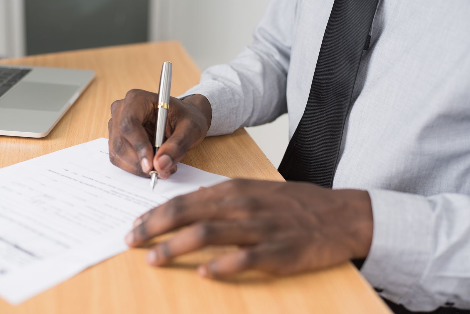 Hands of a company director signing a document digitally at a laptop