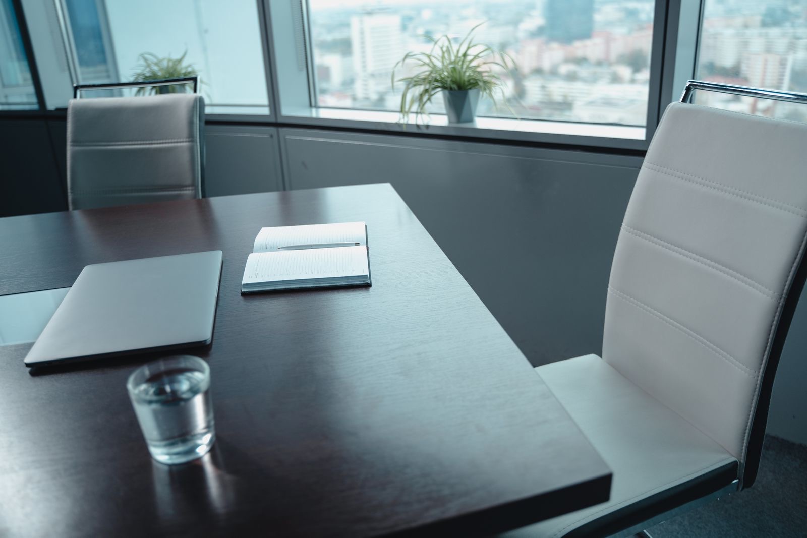 An empty boardroom table with chairs and a laptop