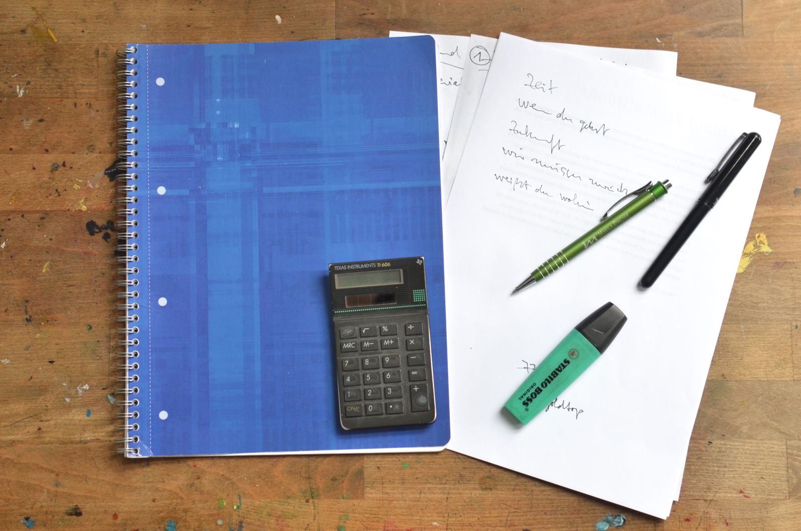 A notebook, pens and a calculator on a desk