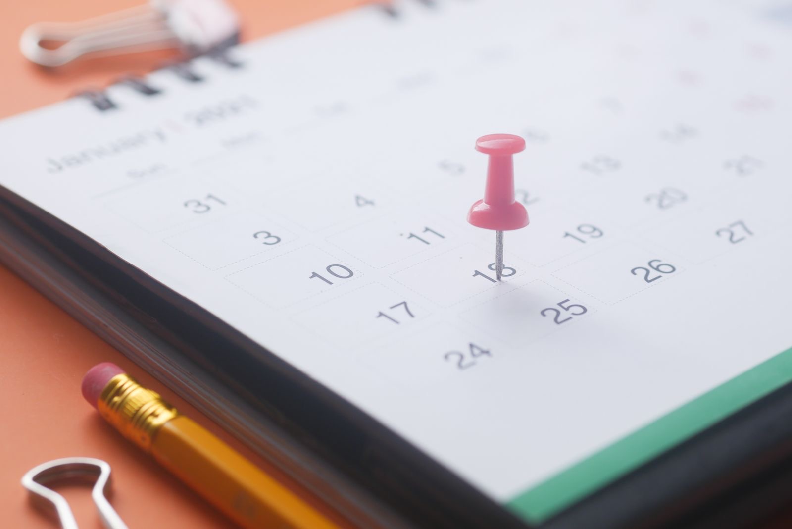 A desk calendar with a date marked, beside a laptop