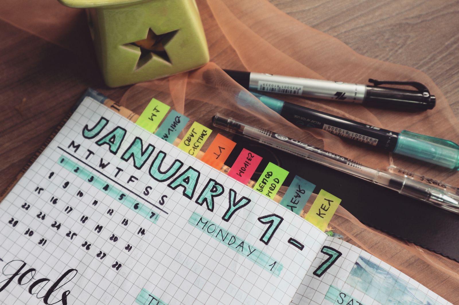 A paper planner calendar and pens on a desk