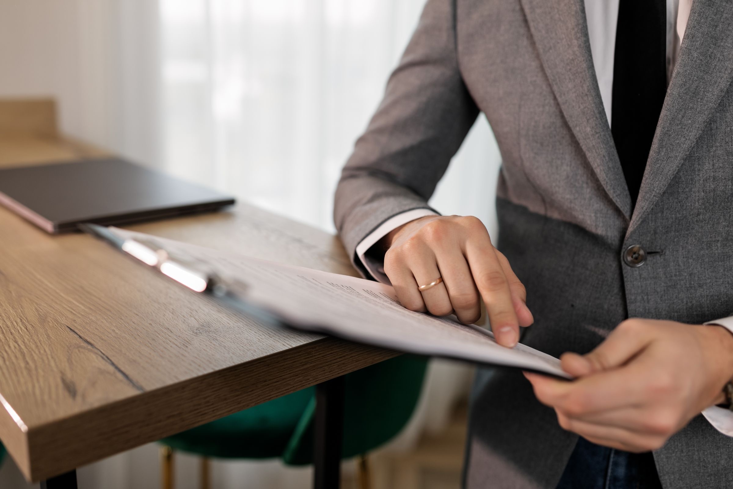 Hands signing a deed at an office table, papers and a pen