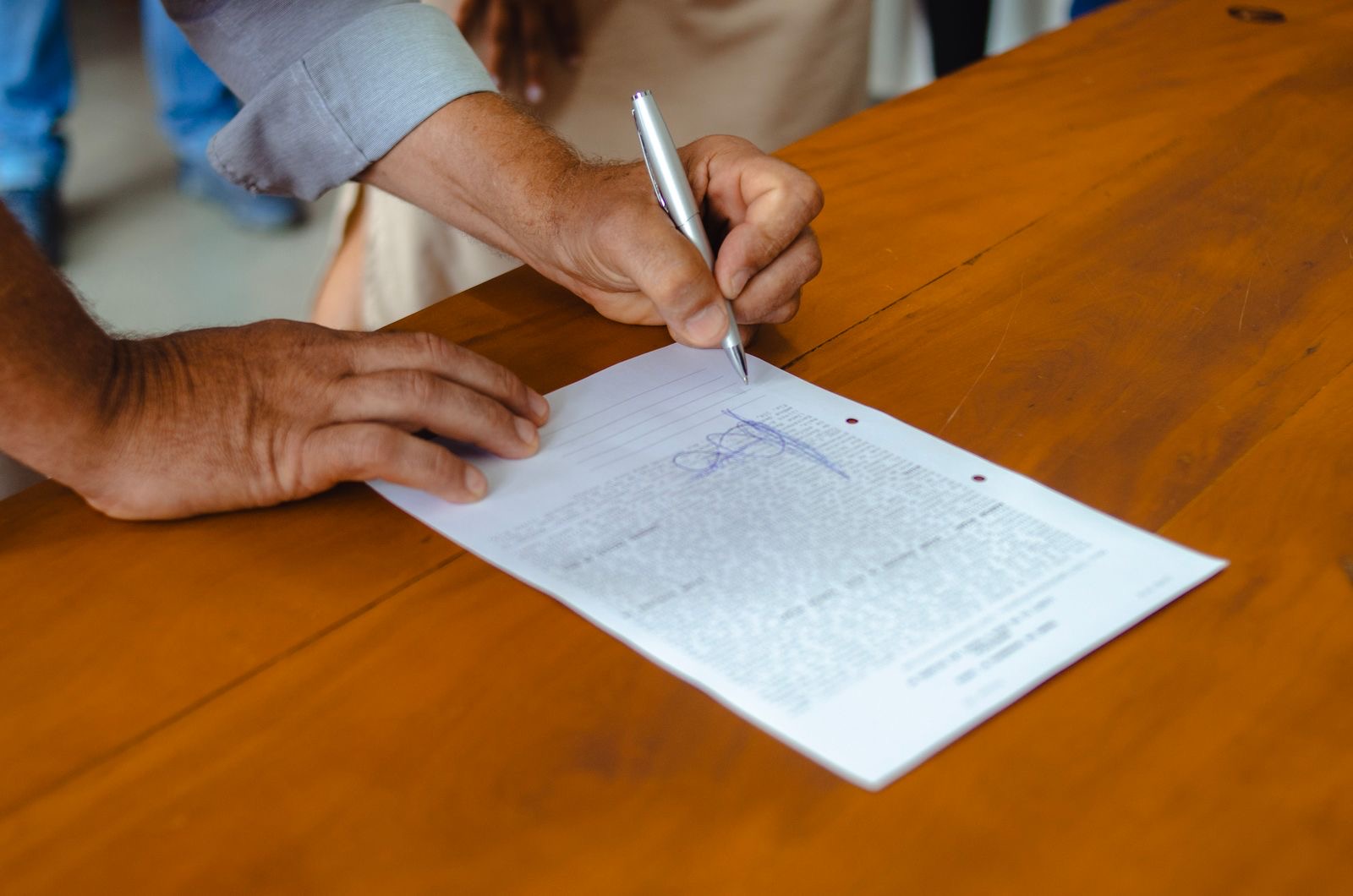 Hands resting on a signed contract on a table
